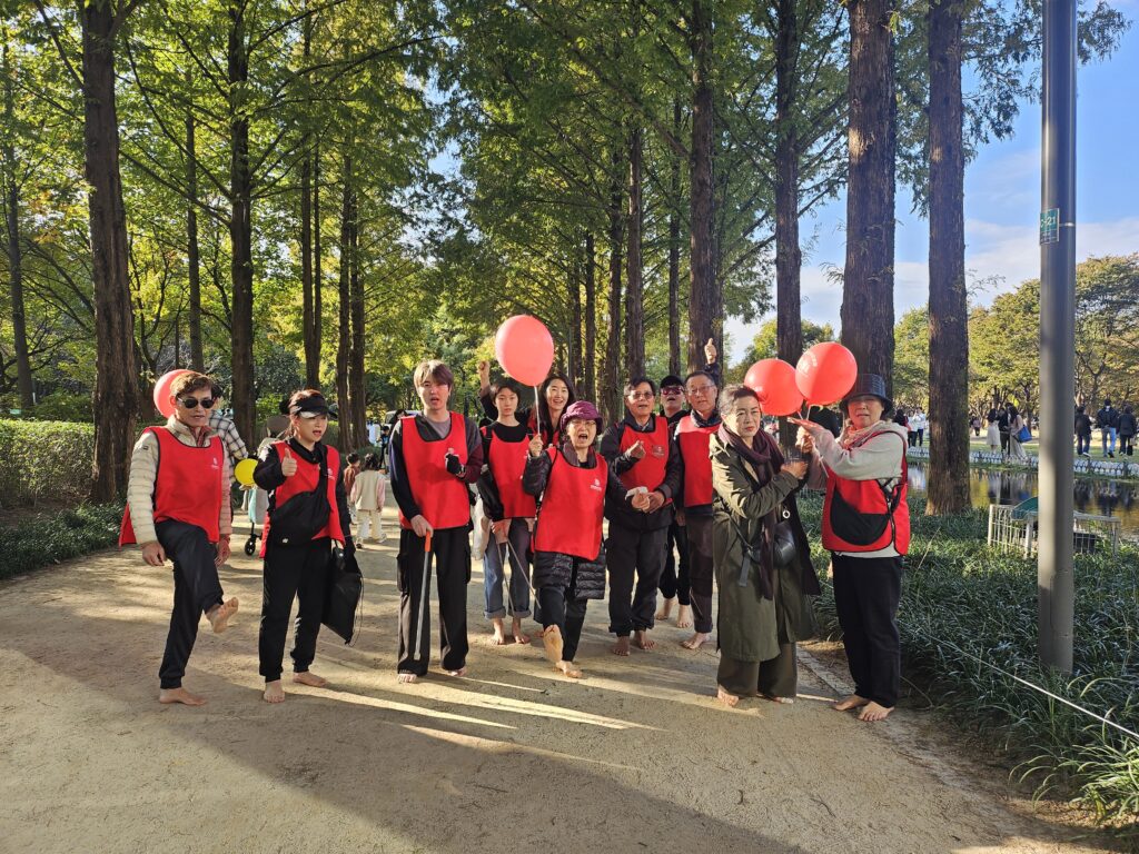 서울숲맨발걷기학교에서 10여명의 회원들이 플로깅 자원봉사자들이 활동을 하고 일어서서 활짝웃으며 서있습니다. 자원봉사 플로깅 1365 인증